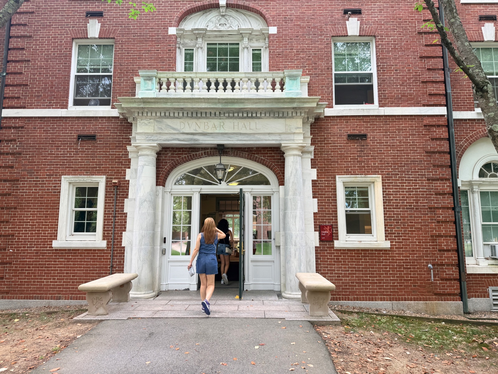 A student walks through the marble doorway of a brick dormitory at Phillips Exeter Academy on move-in day