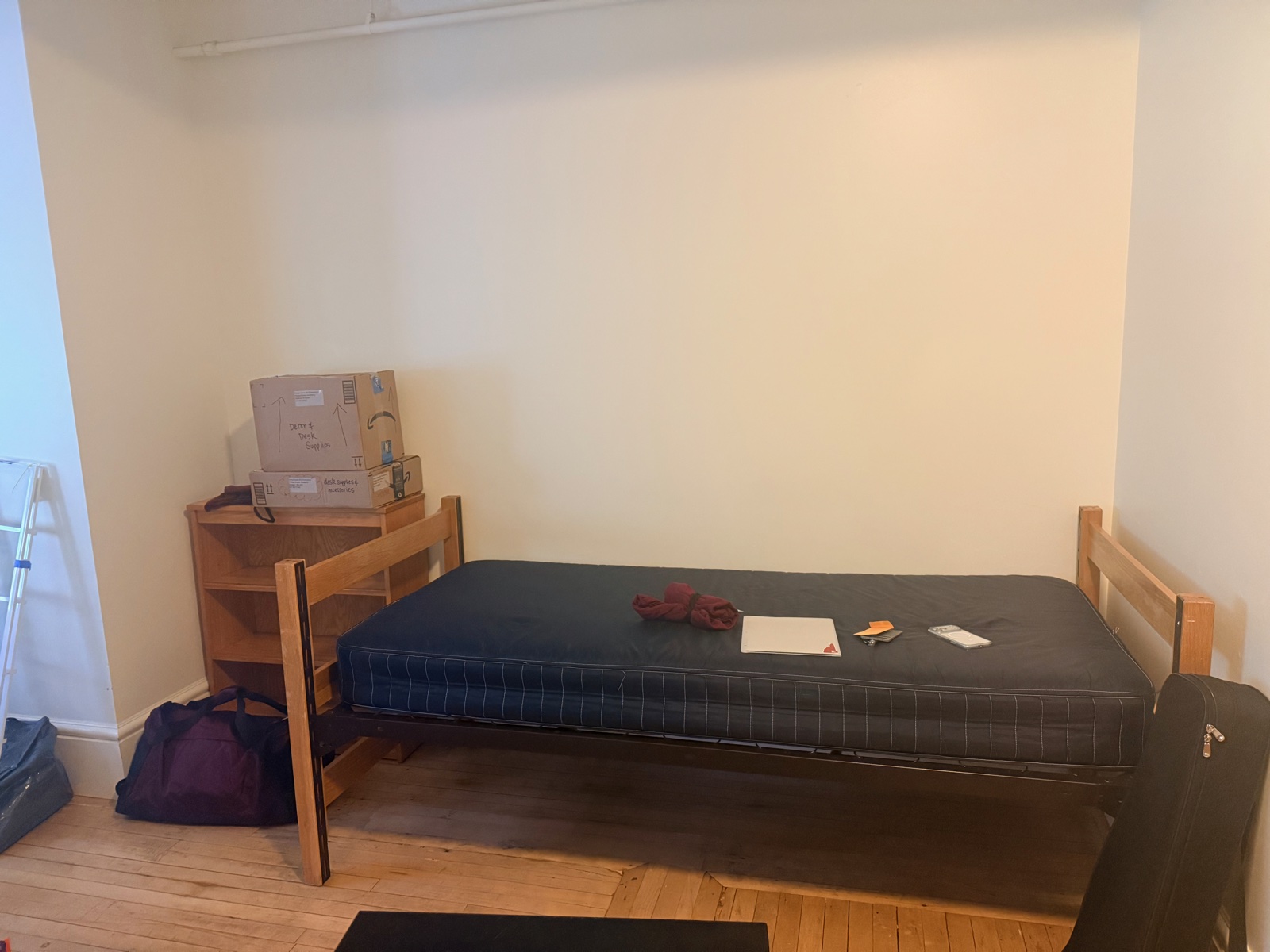 An empty dorm room with a bare mattress, a desk, and a few boxes on move-in morning