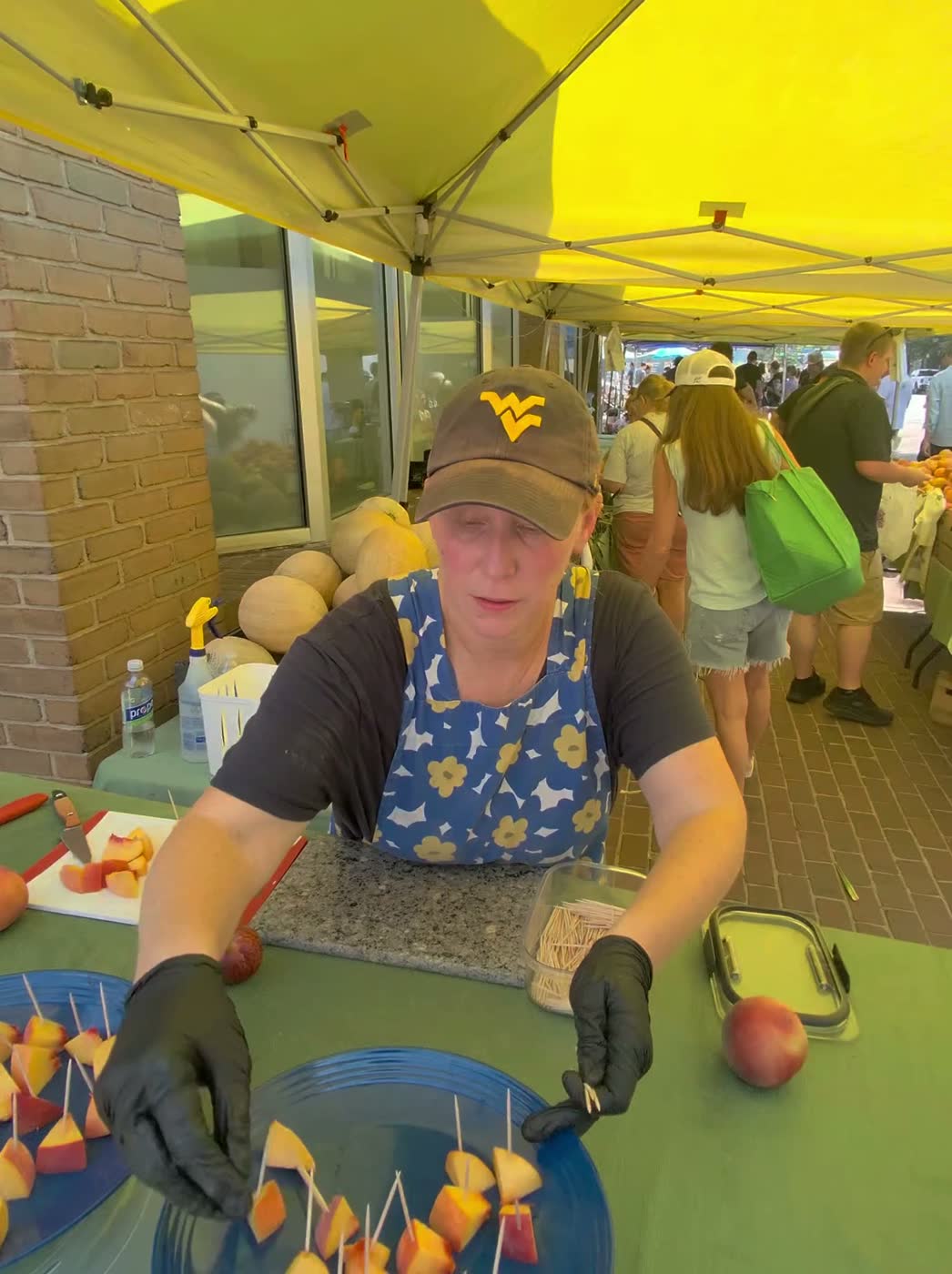 The grower under the yellow tent cutting peach samples on a board and plating them on skewers